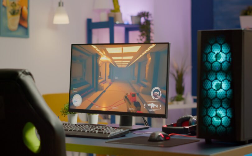 Gaming room no people in equiped with RGB powerful personal computer for online videogames tournament and gaming chair, first-person shooter game on screen. Cozy room with neon light.